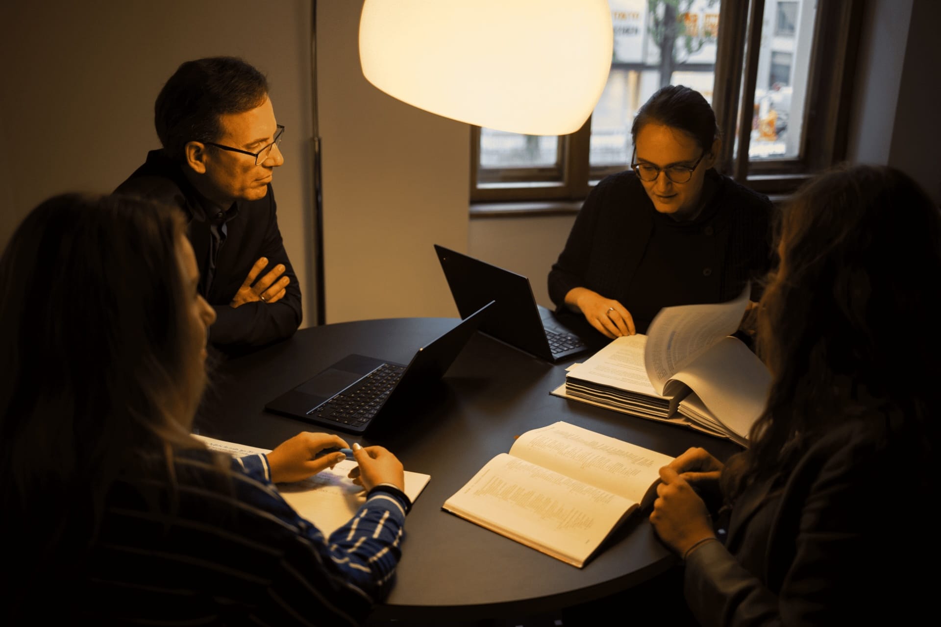 Johannes Kaspar, Carolin Arnemann, Laura Farina Diederichs und Clara Eckardt sitzen diskutierend am Tisch mit Büchern und Laptops vor sich aufgestellt
